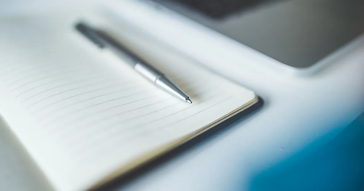 Stylo posé sur un carnet à spirale ouvert, ambiance bureau pour le calcul des cotisations