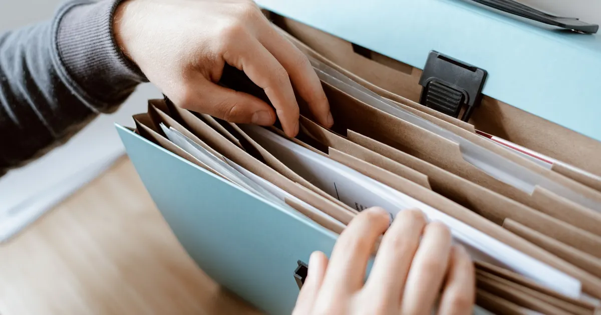 Mains classant des documents dans un trieur à sections, image de l'organisation en 10 sections professionnelles