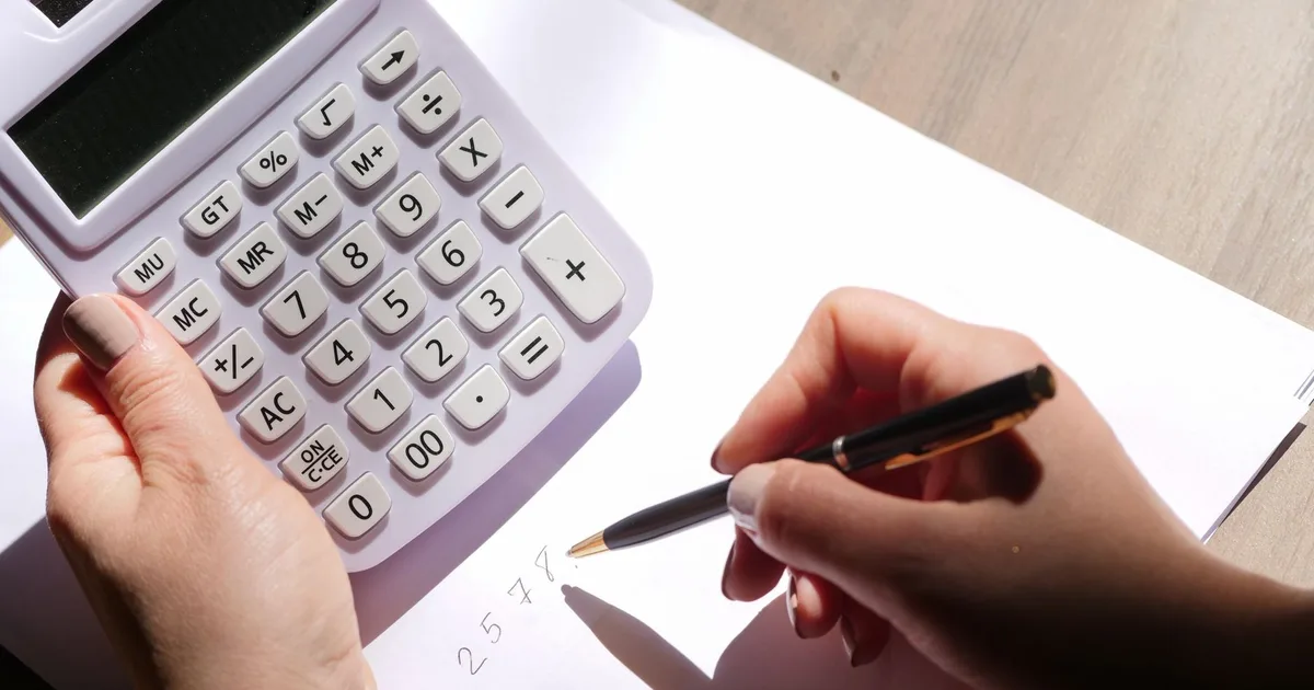 Mains tenant une calculatrice et écrivant des chiffres pour estimer le budget d'une prévoyance dirigeant
