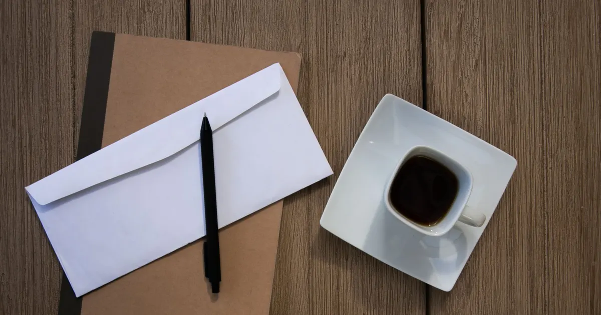 Enveloppe et carnet sur un bureau en bois avec une tasse de café, symbole des documents de succession