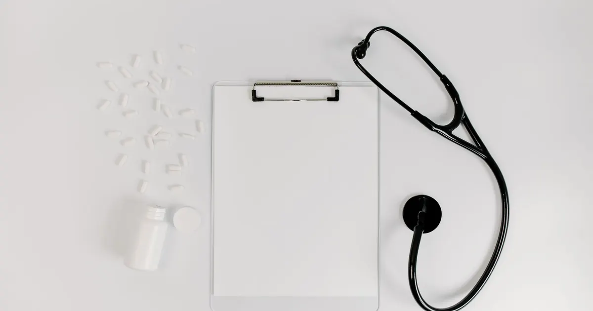 Stéthoscope posé à côté d'un porte-bloc vierge et de médicaments, symbole de l'arrêt de travail