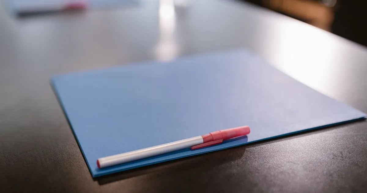 Dossier bleu fermé posé sur un bureau, avec un stylo, symbolisant un contrat Madelin