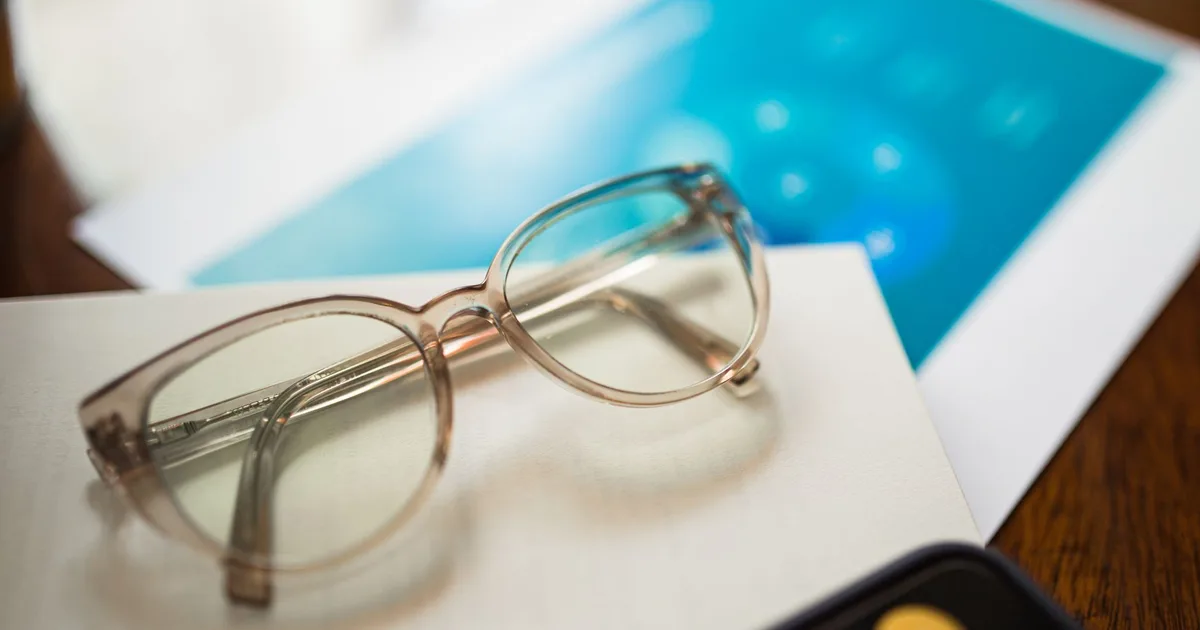 Lunettes de lecture posées sur des documents contractuels pour comparer plusieurs offres Madelin