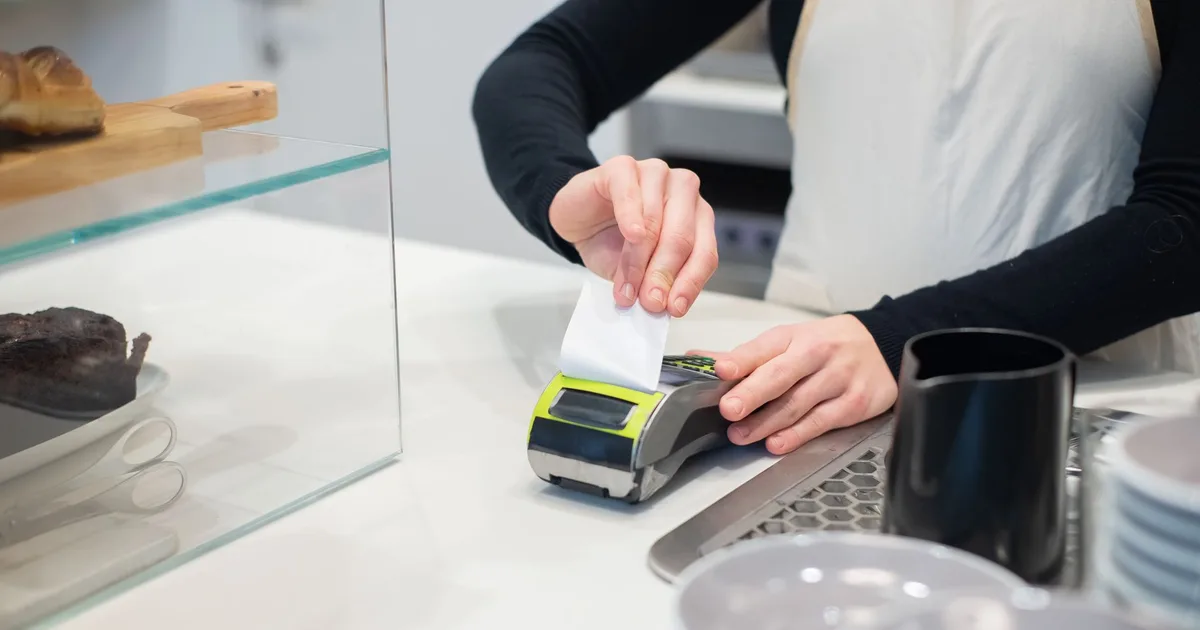 Commerçant encaissant un paiement par carte sur un terminal, illustrant l'activité d'un micro-entrepreneur