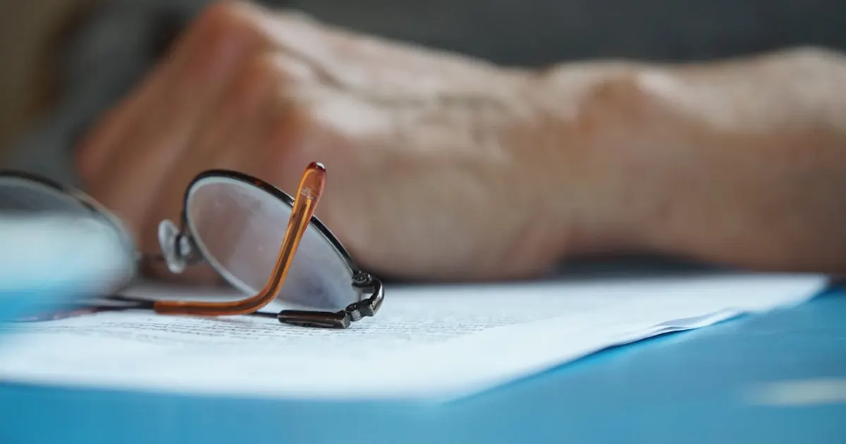 Lunettes de lecture posées sur des documents flous, gros plan sur un bureau