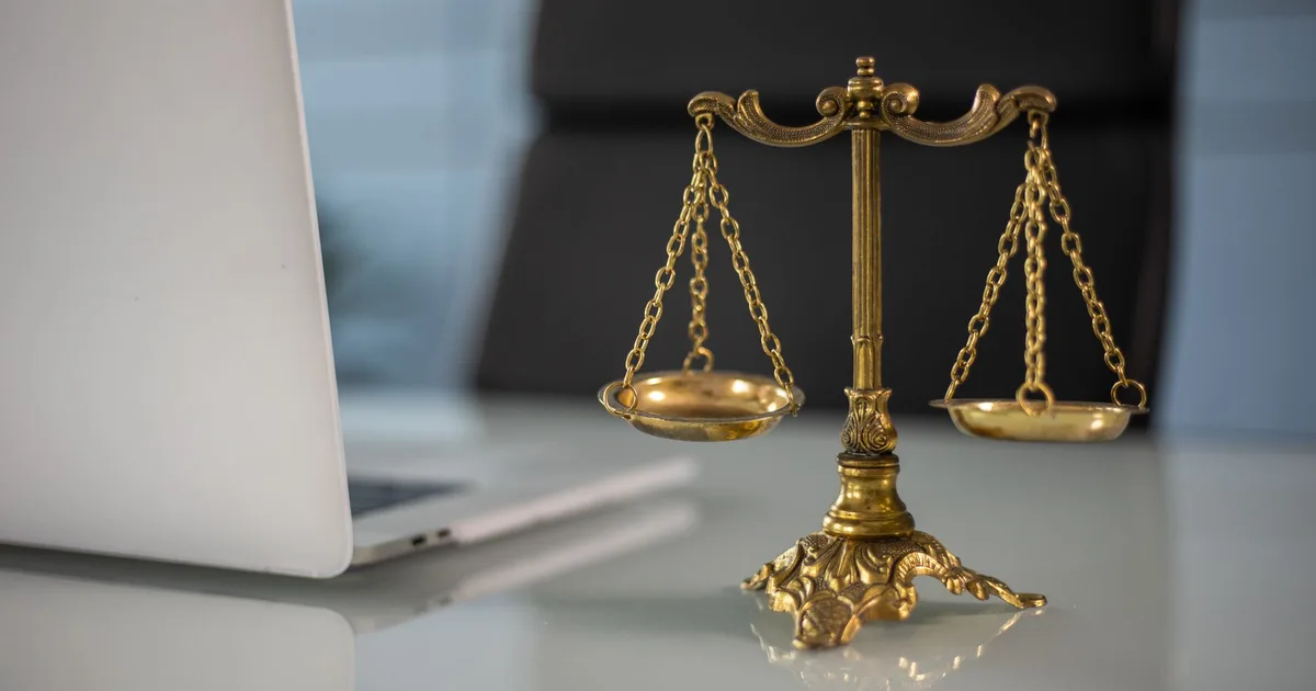 Balance dorée posée sur un bureau à côté d'un ordinateur portable, symbole du comparatif entre deux contrats de prévoyance