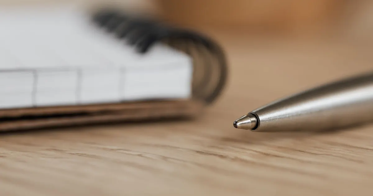 Stylo et carnet à spirale ouvert sur un bureau en bois, cabinet d'orthophonie