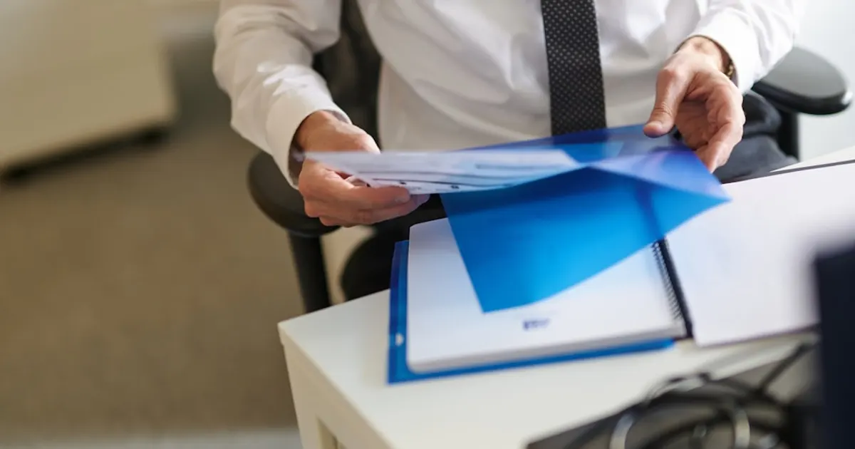 Mains tenant un dossier de documents financiers bleu, symbole du dossier de retraite CAVP
