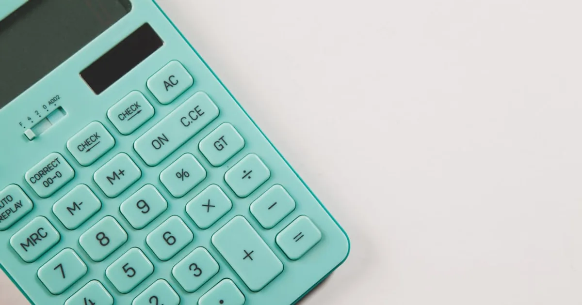 Gros plan mains et calculatrice sur un bureau avec tickets de caisse et documents