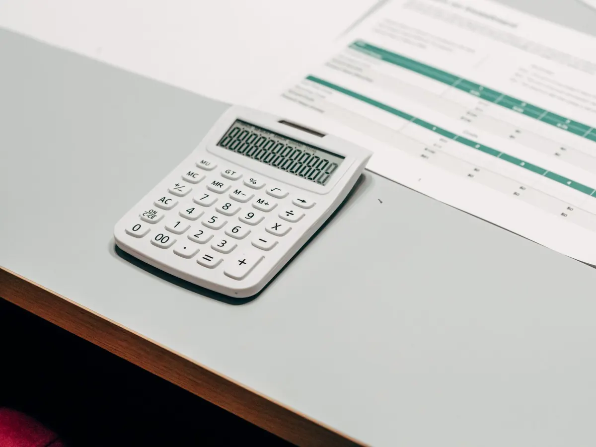 Calculatrice et documents sur un bureau pour estimer le revenu net d'un orthophoniste libéral